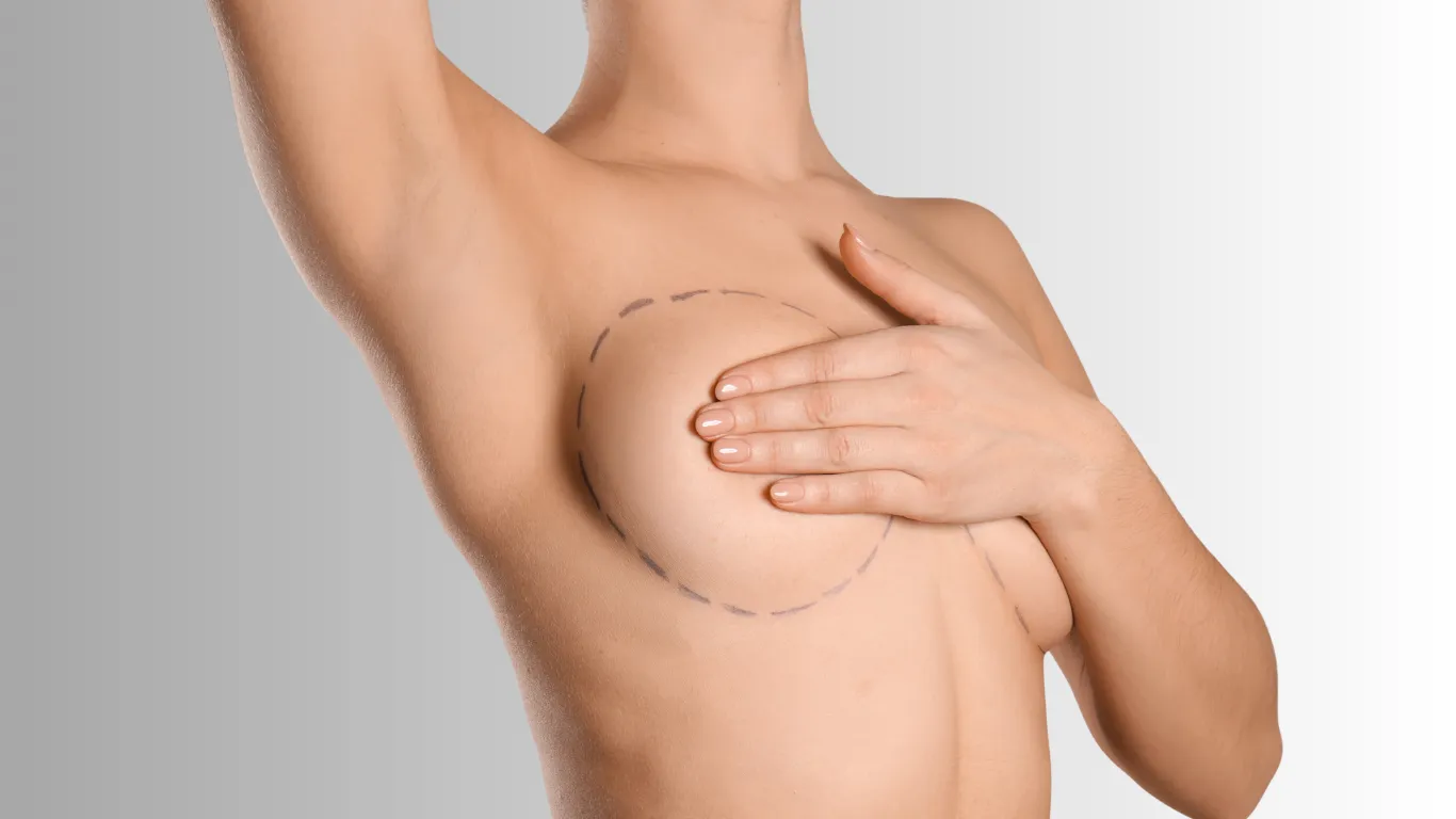 Woman covering her breast with her hand, side view against a gray background
